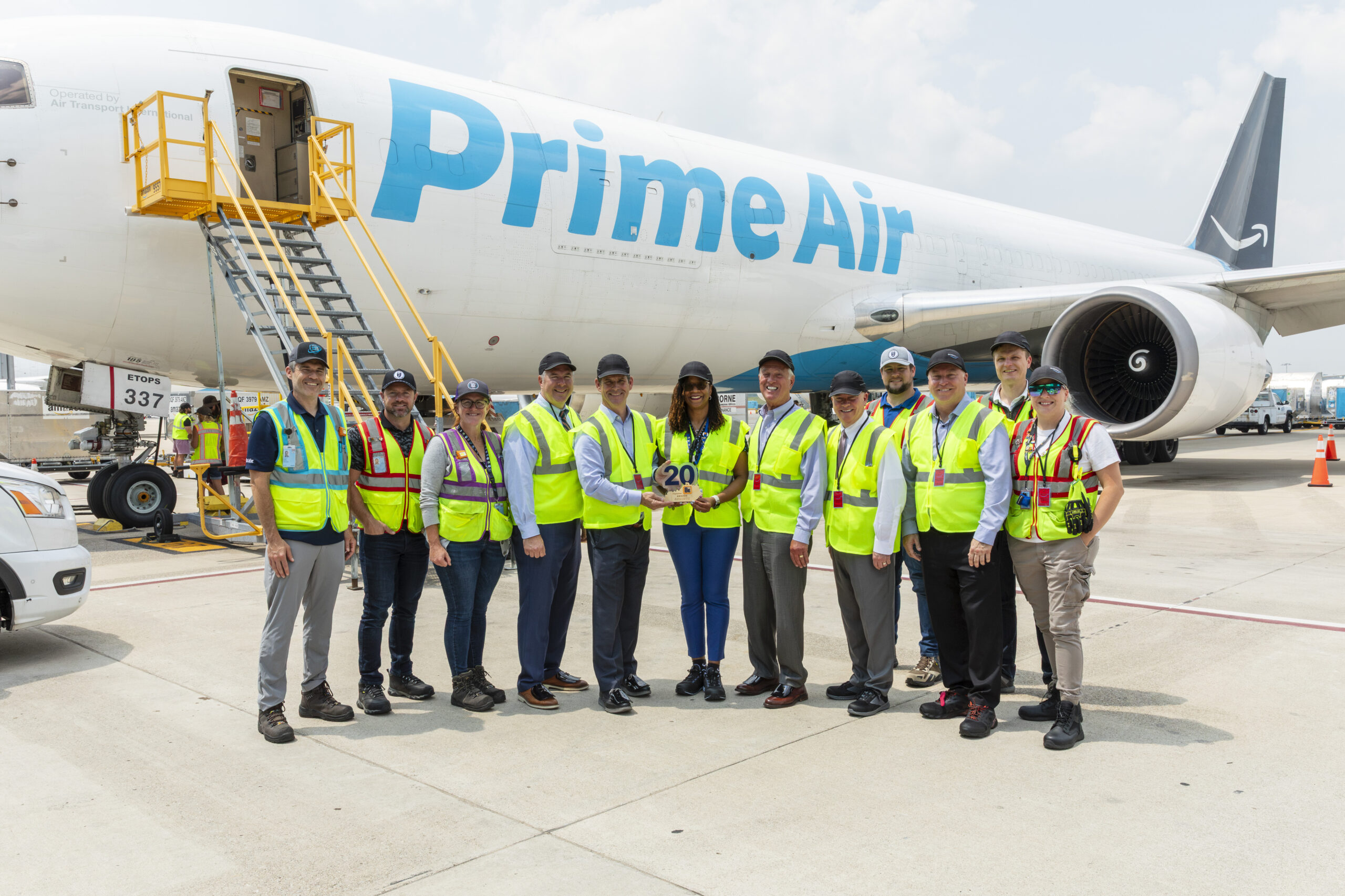 A large group stands in front of an Amazon Air plane for the company's 20th anniversary