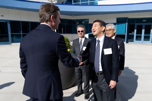 Kentucky Governor Andy Beshear and Osamu Hashimoto from Mitsui Chemical Group greet each other in front of the OneNKY Center